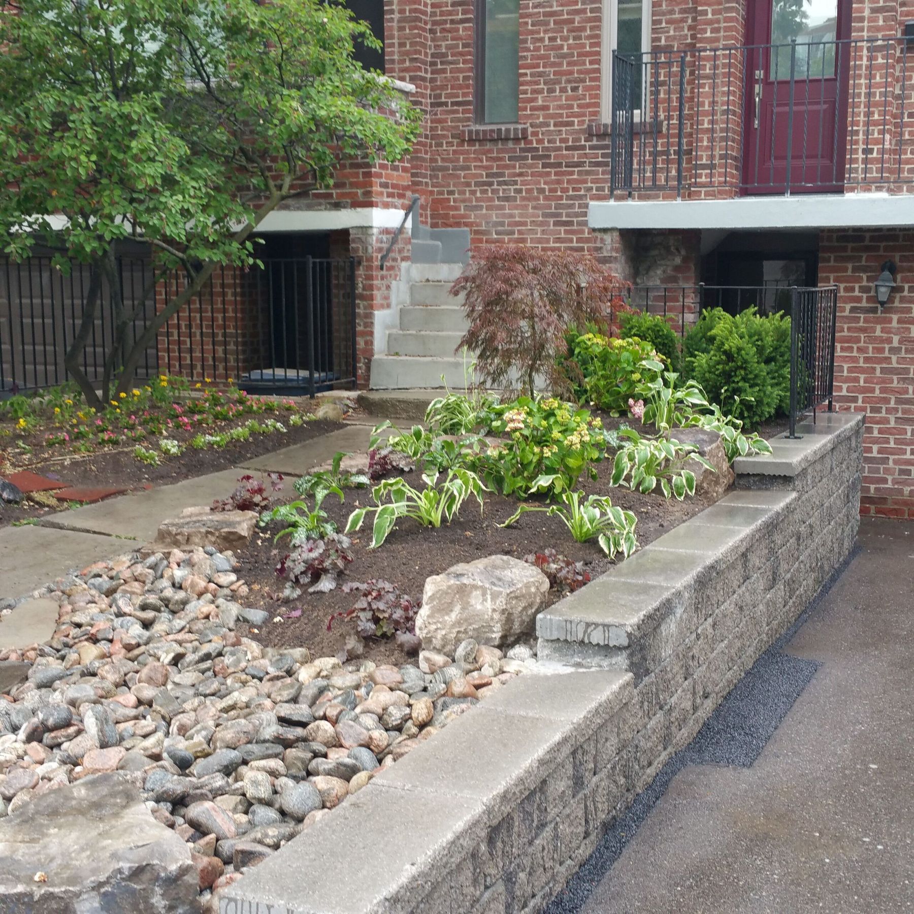 Front-yard retaining wall with river rock and planting