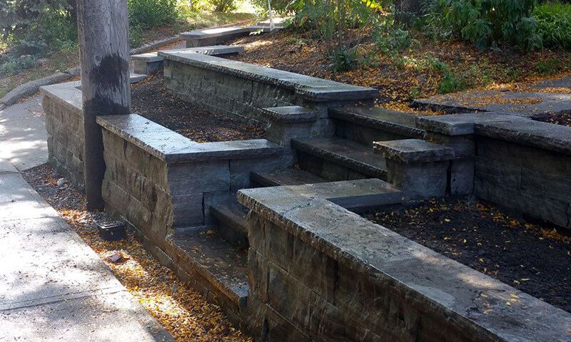 Tiered Eramosa natural stone planter walls stepping down beside a sidewalk