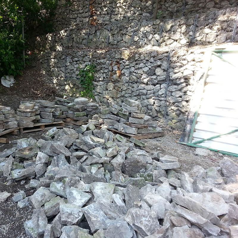 Broken-out wall stone piled on the ground and stacked on pallets during demolition